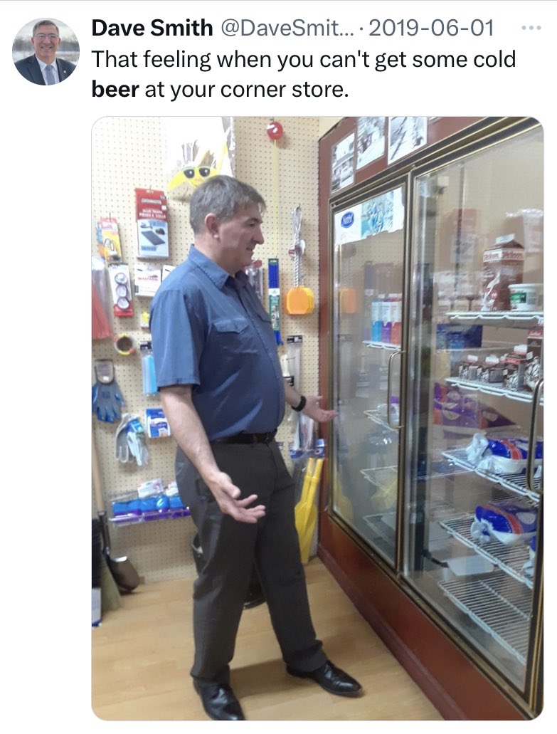 A tweet from MPP Dave Smith from June 2019 shows him standing dumbfounded in front of a refrigerator at a corner store. The text of the tweet says, “That feeling when you can’t get some cold beer at your corner store.”